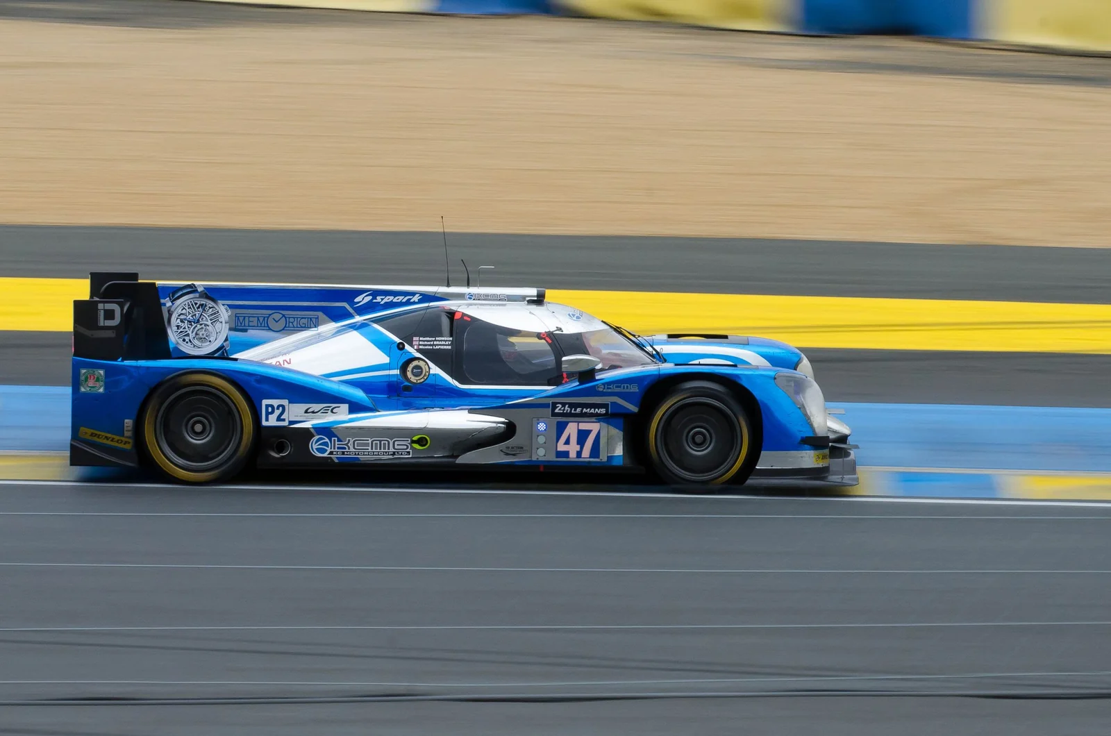 A blue endurance race car speeding along a circuit with the background blurred by panning.